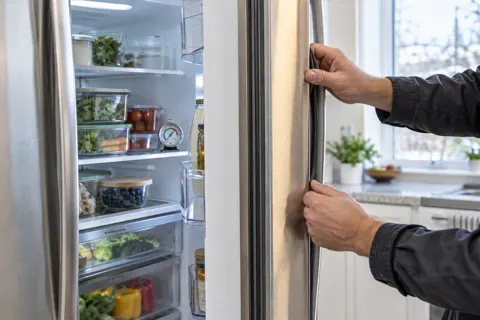Technician checking a refrigerator door seal and thermometer