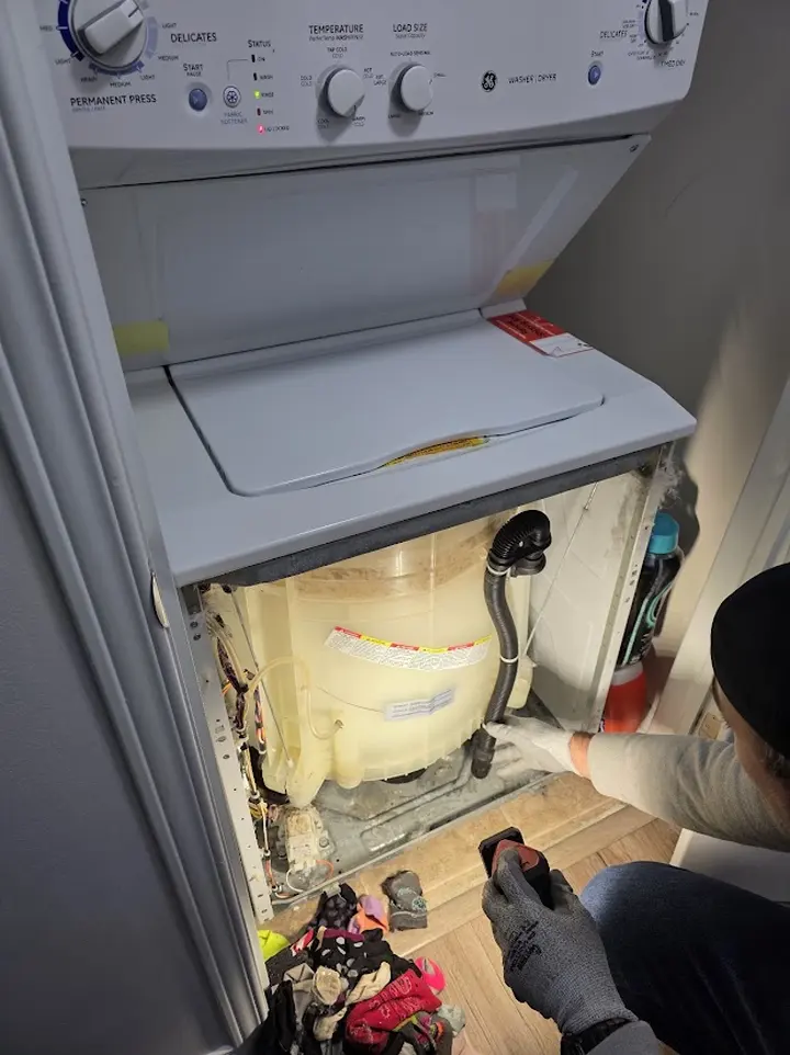 Technician inspecting an opened washing machine during a service visit